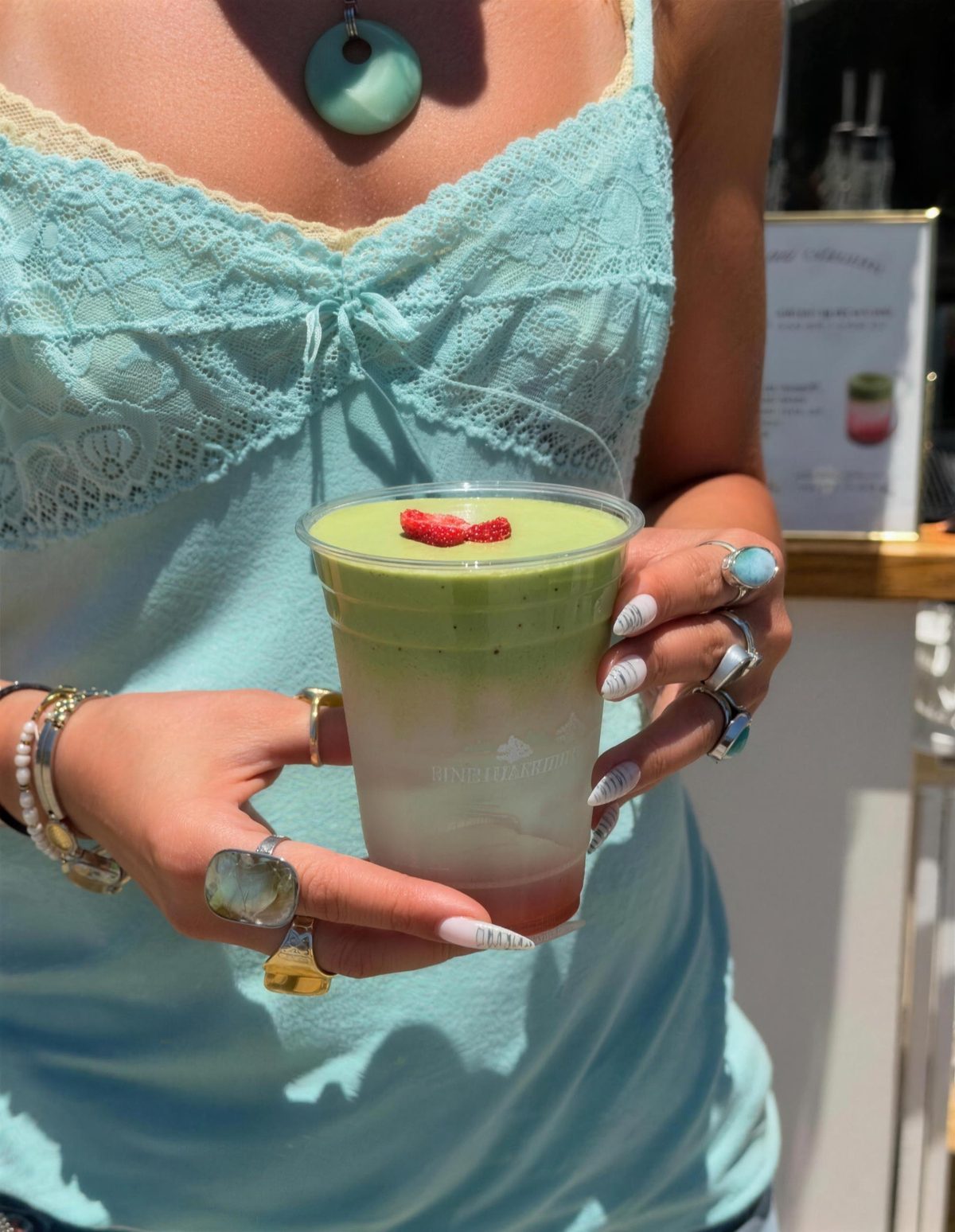 Hand with rings holding a layered matcha with strawberry
