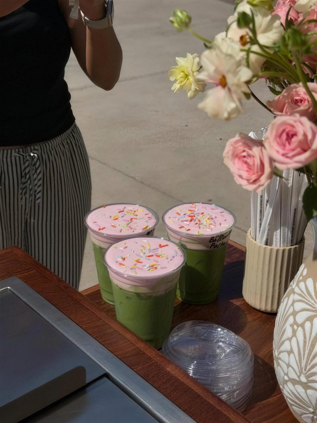 Pink-foam matcha drinks beside roses